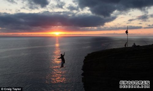 夕阳映衬下，冒险家在巨石间走钢丝
